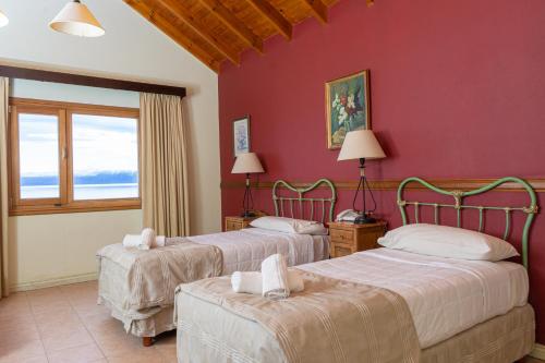 two beds in a room with red walls at Hotel Las Dunas in El Calafate