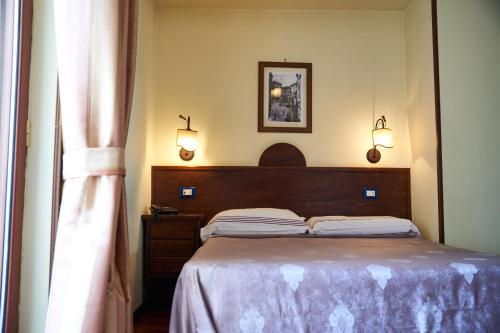 a bedroom with a bed and two lamps and a window at Hotel Max in Aversa