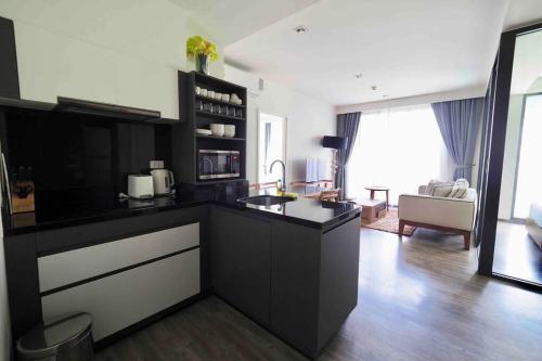 a kitchen with black cabinets and a living room at The Deck patong Luxury Apartments The Deck patong in Patong Beach
