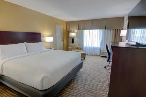 a hotel room with a large bed and a desk at Holiday Inn St. Petersburg N - Clearwater by IHG in Clearwater