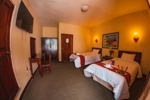 a hotel room with two beds and a desk at Hotel Cajamarca in Cajamarca