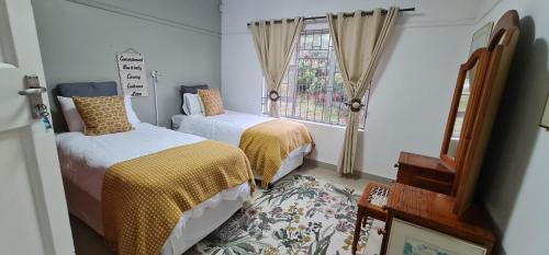 um quarto com 2 camas e uma janela em Cosy Beach House em Port Shepstone