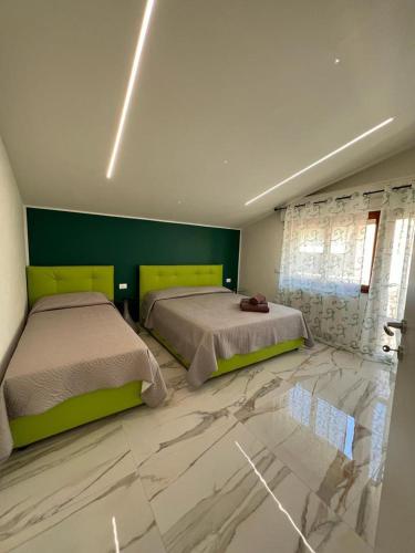 two beds in a bedroom with green walls and marble floors at Casa Bellemo in Chioggia
