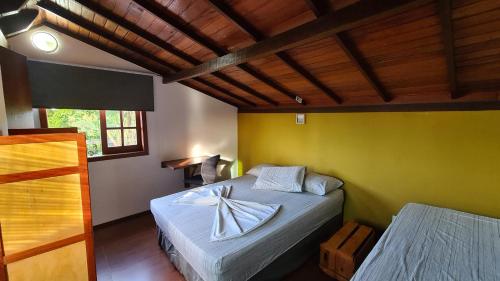 a bedroom with a bed and a yellow wall at Linda Surf House Apartamentos in Itacaré