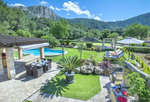 a backyard with a pool and a lawn with plants at Owl Booking Villa Can Demana - Retreat in the Midst of Nature in Pollença
