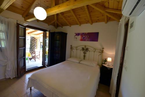 a bedroom with a white bed and a patio at Haus Katerina in Vourvourou