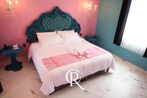 a pink bedroom with a bed with two pink shoes on it at Casa Rosa Hotel & Spa in San Cristóbal de Las Casas