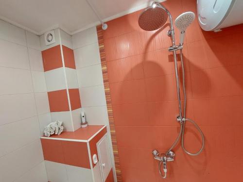a shower in a bathroom with orange and white tiles at Уютен апартамент в сърцето на град Ямбол in Yambol