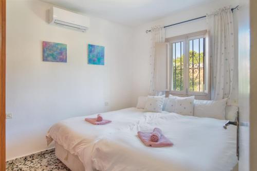 1 dormitorio con cama con chanclas rosas en El Arroyuelo, en Estepona