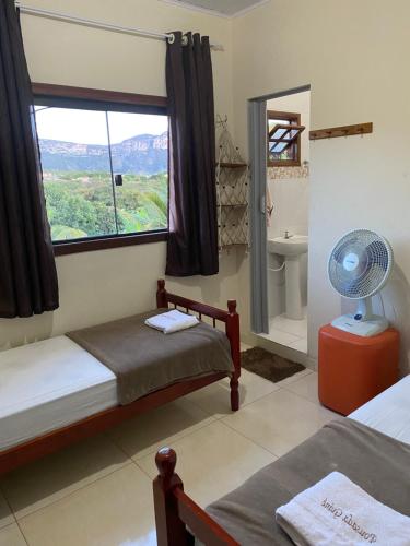 a bedroom with two beds and a window and a fan at Pousada Guiné in Mucugê