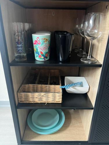 a shelf with plates and wine glasses and a basket at Cocon Accès facile Parking Gratuit in Belfort