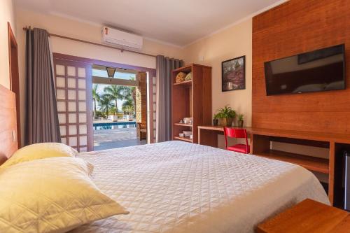 a bedroom with a bed with a television and a desk at Hotel Imperium Village in Sarapuí