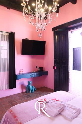 a bedroom with a pink wall with a bed and a tv at Casa Rosa Hotel & Spa in San Cristóbal de Las Casas