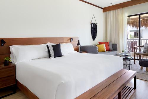 a bedroom with a large white bed and a living room at Kimpton Aluna Resort Tulum by IHG in Tulum