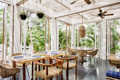 a dining room with a table and chairs and windows at Kimpton Aluna Resort Tulum by IHG in Tulum