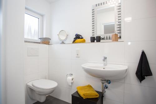 a white bathroom with a toilet and a sink at NaturTraum in Winterberg