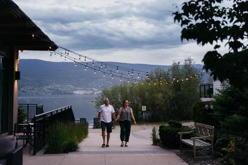two people walking down a sidewalk next to a body of water at Summerland Waterfront Resort & Spa in Summerland