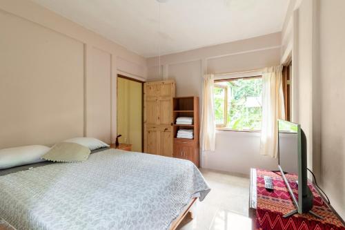 a bedroom with a bed and a window and a television at Casa Chilamates 2.0 in Tortuguero