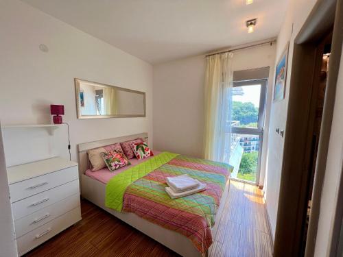a small bedroom with a bed and a window at Apartment Maestral with sea view in Pržno
