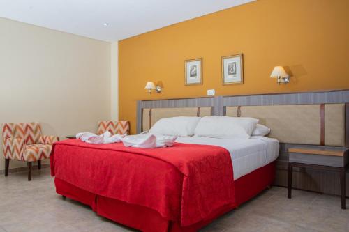a bedroom with a large bed with a red blanket at Hotel Las Dunas in El Calafate