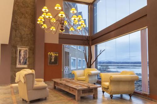 a living room with chairs and a table and a chandelier at Hotel Las Dunas in El Calafate