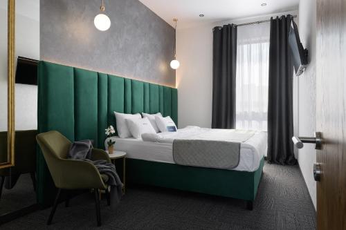 a bedroom with a bed with a green headboard and a chair at Ribas Rooms Bila Tserkva in Bila Tserkva