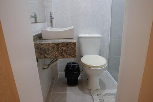a bathroom with a white toilet and a sink at Rodeio Hotel in Rodeio Bonito