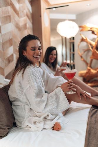 two women sitting on a bed with a drink at Domaine Des Hautes Fagnes in Ovifat