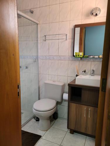 uma casa de banho com um WC, um lavatório e um espelho. em Suíte Lago Negro em Gramado
