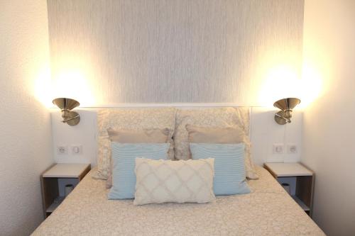 Un dormitorio con una cama con dos luces. en L'Aigue-Marine emplacement parfait, parking privé, en Arzon