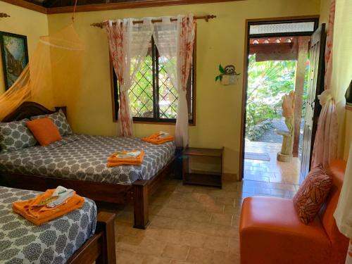a room with two beds and a couch and a window at Cabinas Tito in Cahuita