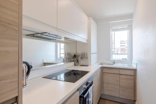 a kitchen with white countertops and a window at Marylebone Gloucester Place Apartments in London