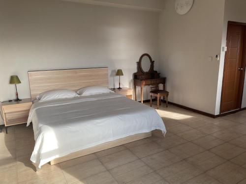a bedroom with a large white bed and a table at Kirin Guesthouse and Restaurant in Port Louis