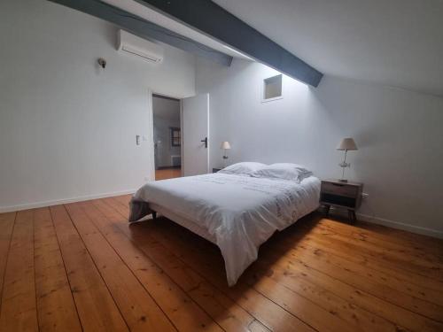 une chambre blanche avec un lit et un parquet dans l'établissement La Marceline 1 - Appart entre mer et canal du midi en pays Cathare, à Saint-Marcel