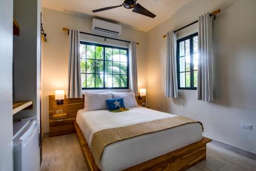 a bedroom with a large bed with two windows at The Sea Glass Inn in Placencia Village