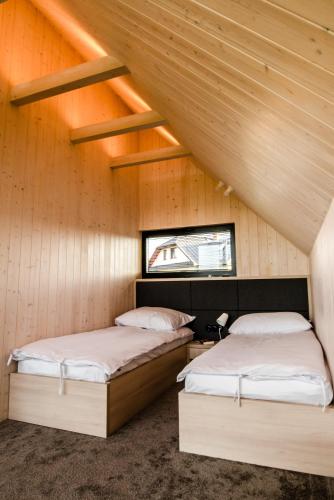 two beds in a room with wooden walls at Czarne Domki in Zwierzyniec
