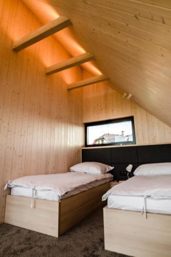 two beds in a room with wooden walls at Czarne Domki in Zwierzyniec