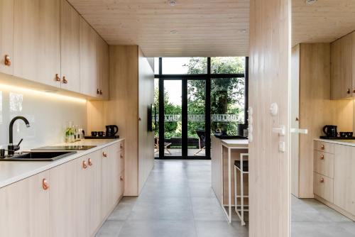 a kitchen with wooden cabinets and a large window at Czarne Domki in Zwierzyniec