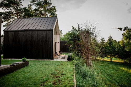 a black shed with a black roof in a yard at Czarne Domki in Zwierzyniec