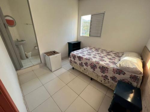 a small bedroom with a bed and a bathroom at Pousada Arco-Íris in Guarujá
