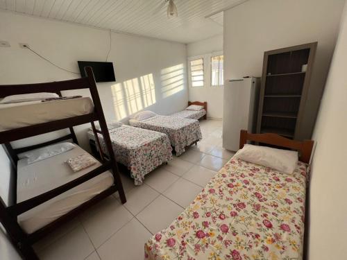 a room with three bunk beds and a refrigerator at Pousada Arco-Íris in Guarujá
