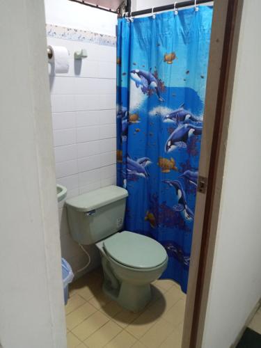 baño con aseo y cortina de ducha azul en Hospedaje Santa Bárbara, en Buga