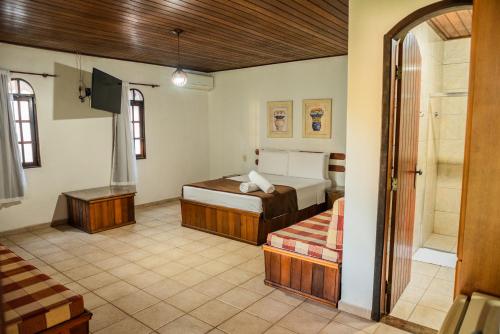 a bedroom with two beds and a tub in it at Pousada Tapera in Penedo