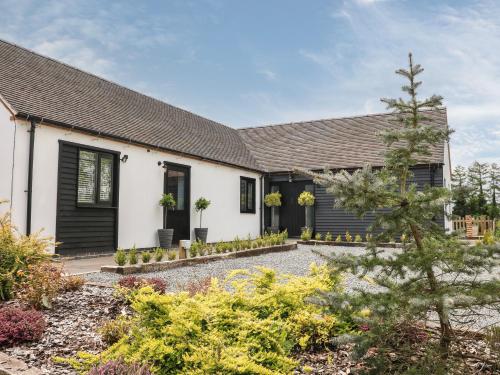 a house with black shutters and a garden at The Den, Bank Top Farm in Ashbourne