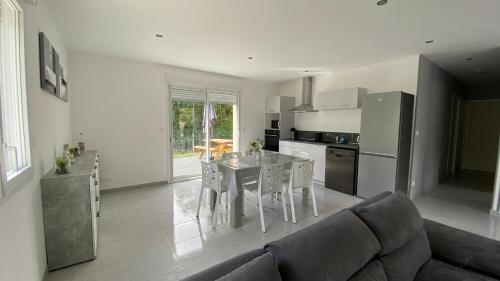 een keuken en een woonkamer met een tafel en een bank bij Maison au cœur de la nature in Cerisy-la-Forêt