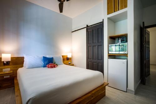 a bedroom with a large white bed and a refrigerator at The Sea Glass Inn in Placencia