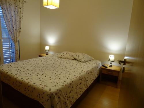 a bedroom with a bed and two night stands with lamps at SUDWEST ROOMS by Stay in Alentejo for HIKERS in Vila Nova de Milfontes