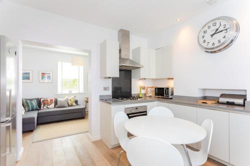 a kitchen and living room with a clock on the wall at Coastguard Cottage in Milford on Sea