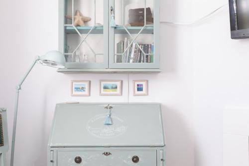 a cabinet above a white dresser in a room at Coastguard Cottage in Milford on Sea