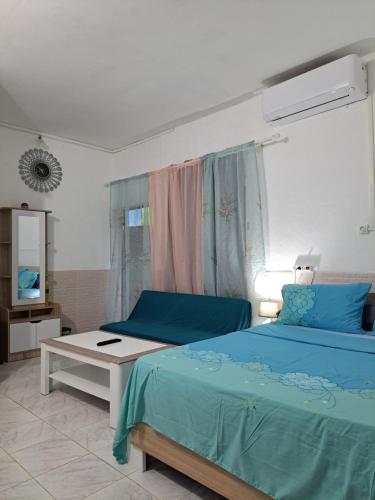 Un dormitorio con una cama azul y una mesa en STUDIOS BAMBO-EST Sunrise en Bandrélé